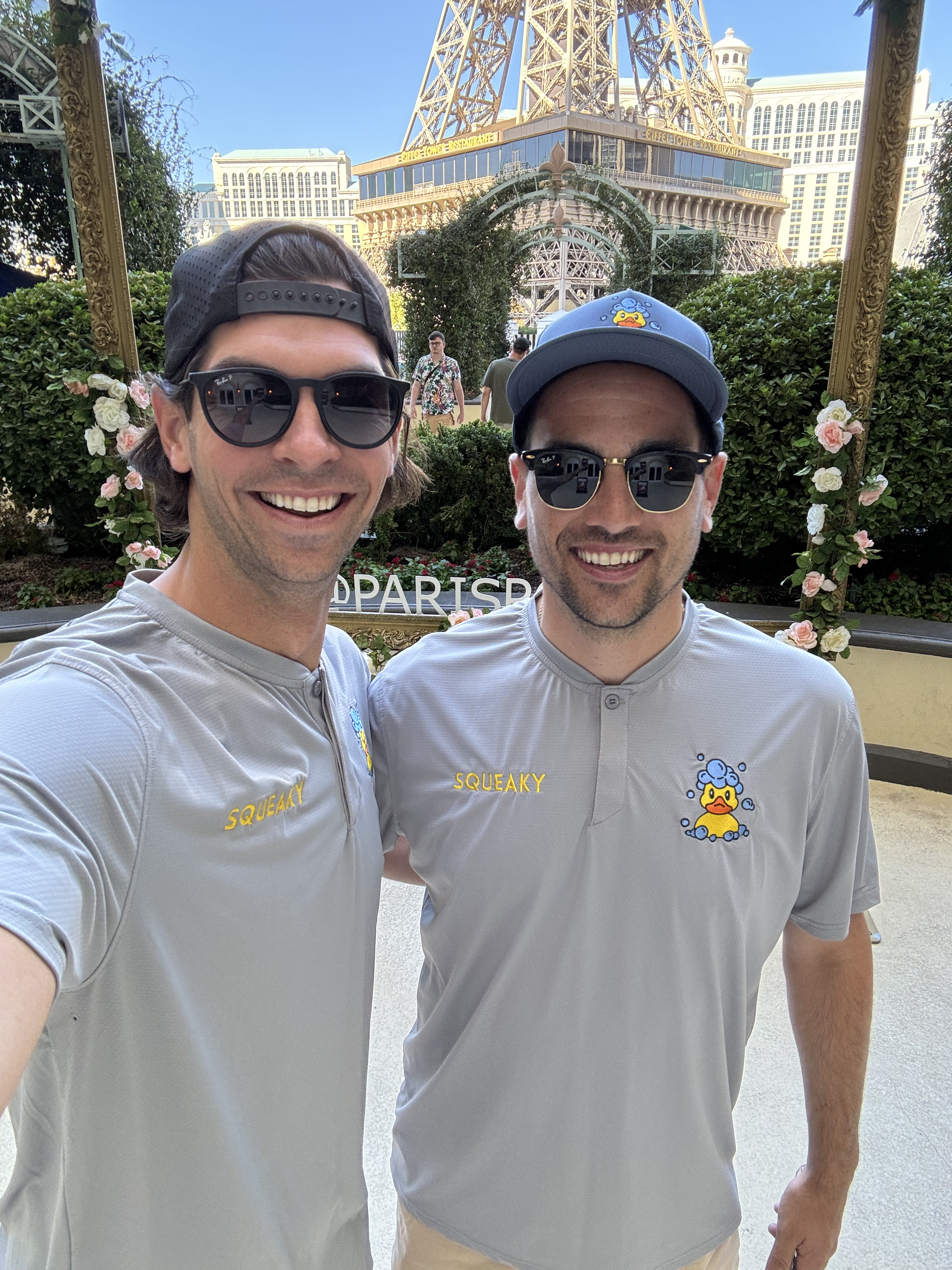Two Squeaky team members in duck-logo uniforms at a Las Vegas landmark