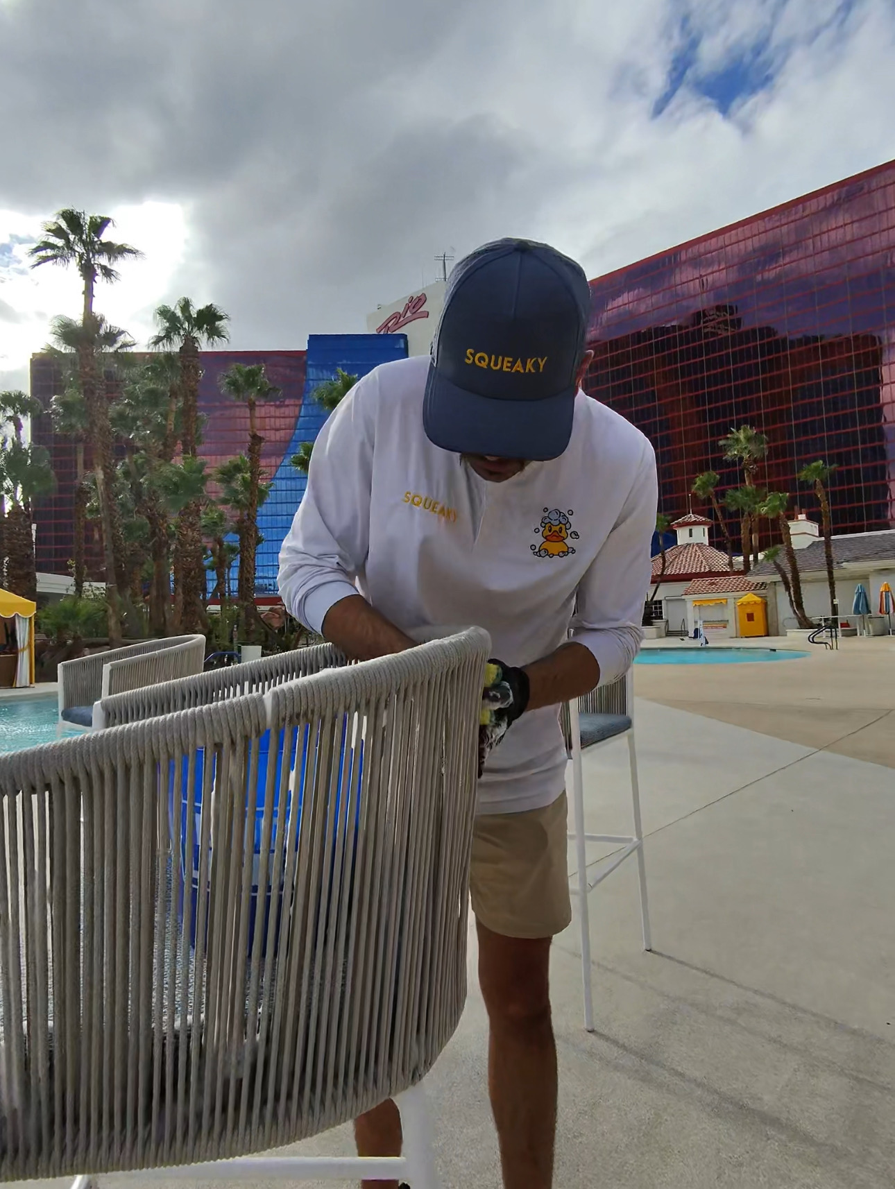 Squeaky technician wiping down a rope chair on a pool deck